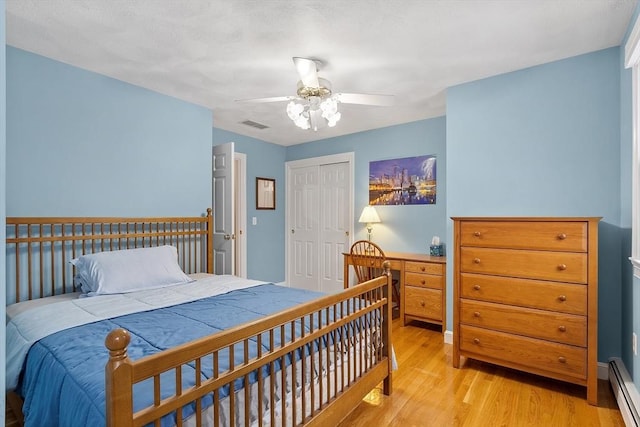 bedroom with a closet, visible vents, baseboard heating, light wood-style floors, and a ceiling fan