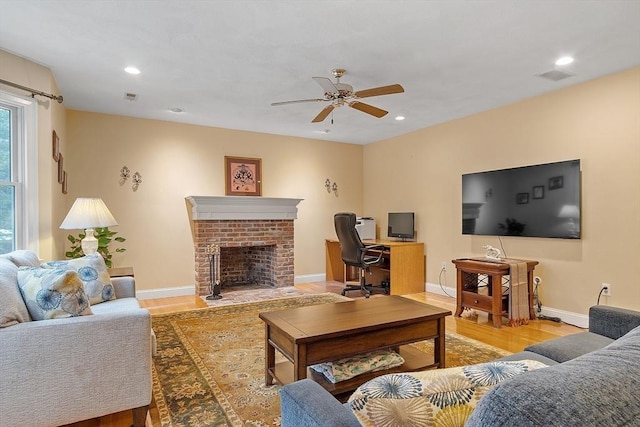 living area featuring a brick fireplace, visible vents, wood finished floors, and recessed lighting