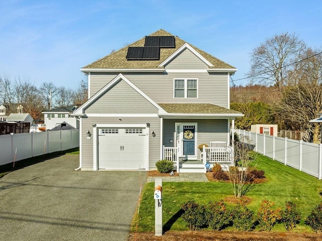 view of front facade featuring a porch, a garage, a front yard, and solar panels