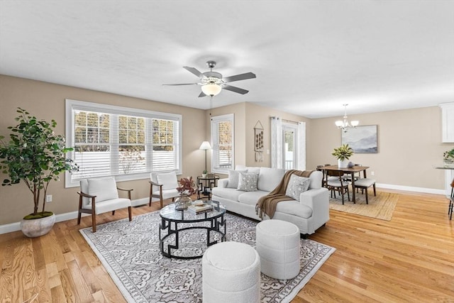 living room featuring ceiling fan with notable chandelier and light hardwood / wood-style floors