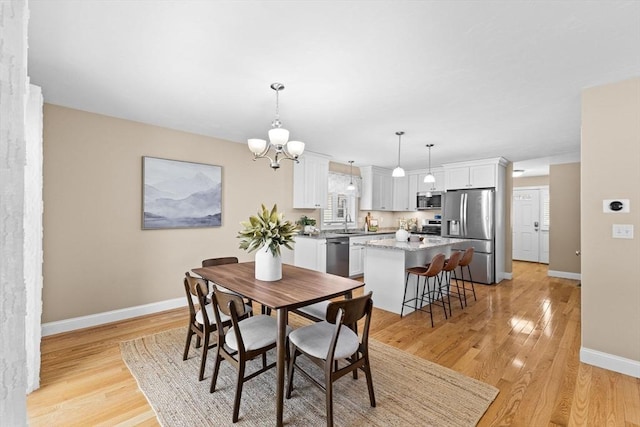 dining area with sink, an inviting chandelier, and light hardwood / wood-style flooring