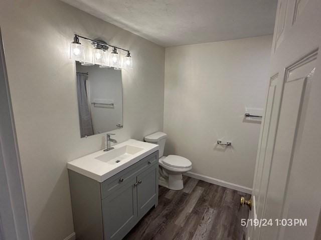 bathroom with wood-type flooring, vanity, and toilet