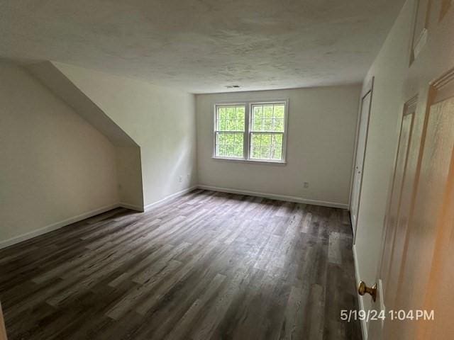 additional living space with dark wood-type flooring and a textured ceiling