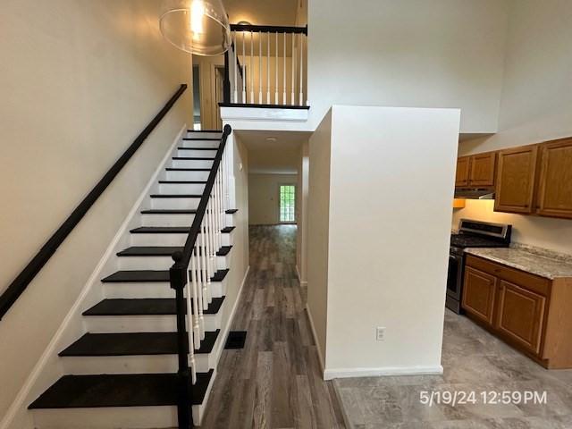 stairway featuring wood-type flooring and a high ceiling