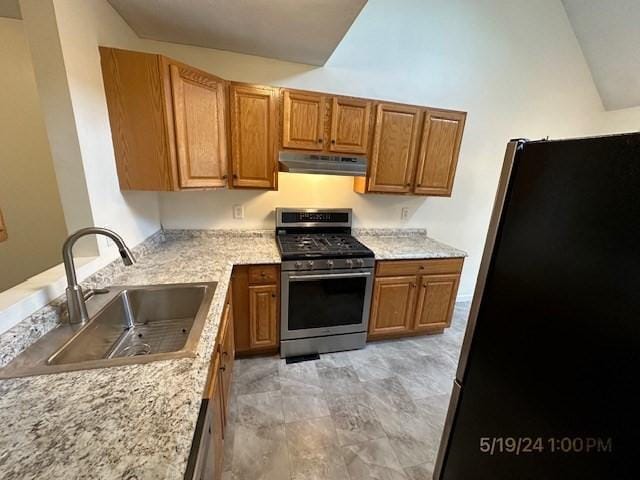 kitchen with appliances with stainless steel finishes, sink, lofted ceiling, and light stone counters