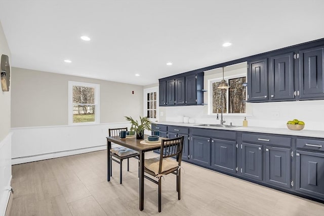 kitchen with blue cabinetry, a baseboard radiator, hanging light fixtures, and sink