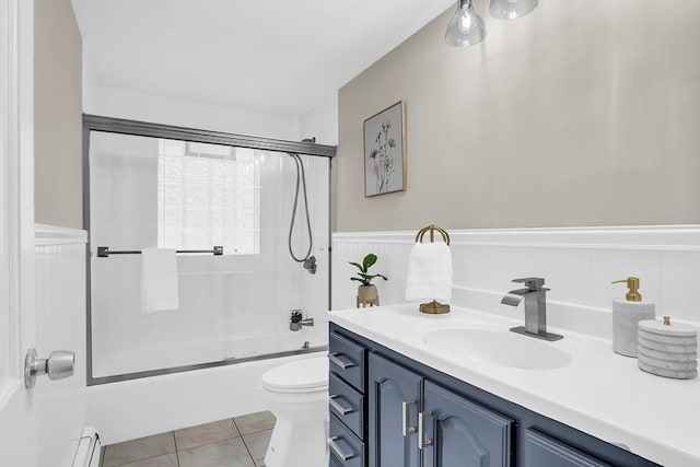 full bathroom with a baseboard heating unit, tile patterned floors, toilet, shower / bath combination with glass door, and vanity