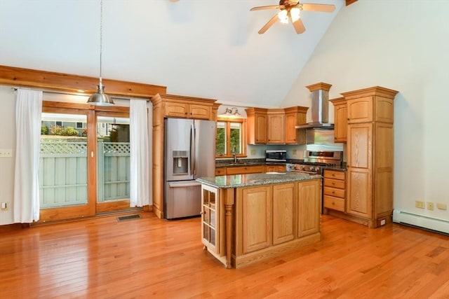 kitchen featuring wall chimney range hood, a baseboard radiator, appliances with stainless steel finishes, high vaulted ceiling, and a kitchen island
