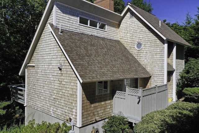 exterior space with a chimney and a shingled roof