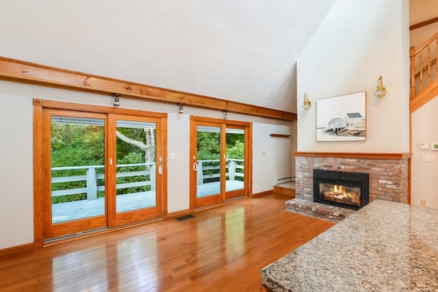 living room with a wealth of natural light, a baseboard radiator, light wood-type flooring, and a fireplace