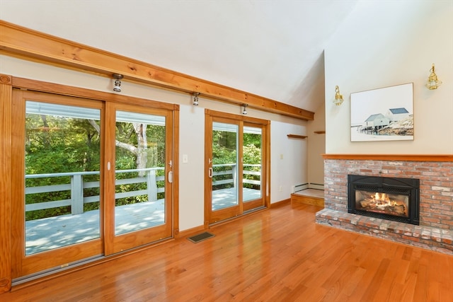 unfurnished living room featuring plenty of natural light, baseboard heating, hardwood / wood-style floors, and a fireplace