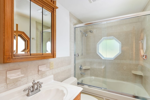 full bathroom featuring toilet, a wealth of natural light, combined bath / shower with glass door, and vanity