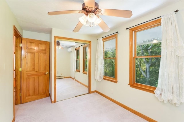 unfurnished bedroom with ceiling fan, a wall unit AC, light colored carpet, a closet, and baseboards