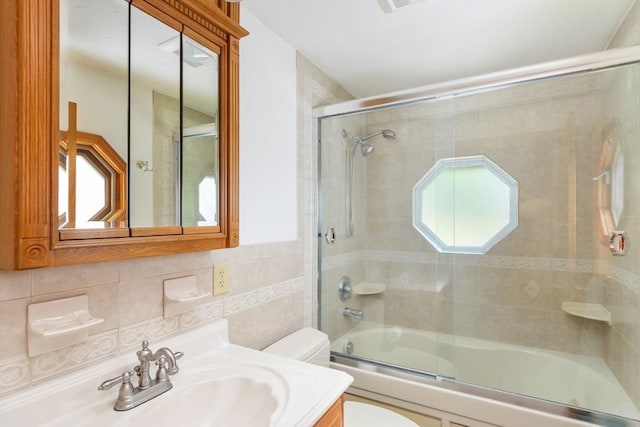 full bath featuring enclosed tub / shower combo, vanity, tile walls, and toilet
