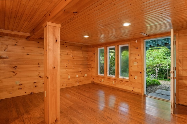 empty room with wooden ceiling, light hardwood / wood-style flooring, and wooden walls