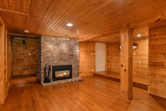 unfurnished living room featuring track lighting, a fireplace, wooden ceiling, and light wood-type flooring