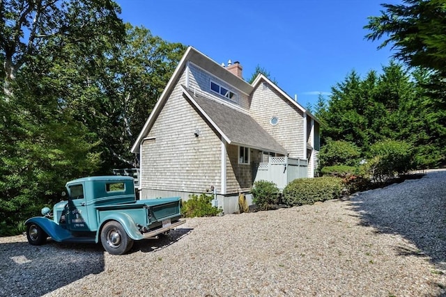 view of property exterior with roof with shingles and a chimney