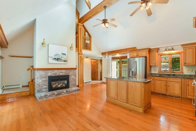 kitchen with stainless steel fridge with ice dispenser, plenty of natural light, a sink, high vaulted ceiling, and a kitchen island
