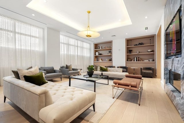 interior space featuring a tray ceiling, built in features, and light wood-type flooring