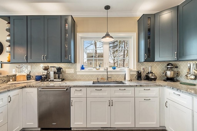 kitchen featuring tasteful backsplash, crown molding, decorative light fixtures, light stone counters, and a sink