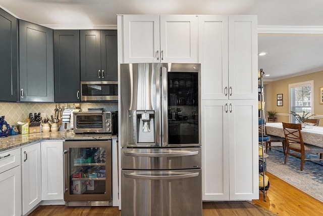 kitchen featuring wood finished floors, stainless steel appliances, wine cooler, a toaster, and decorative backsplash