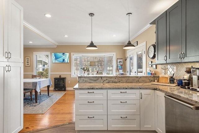 kitchen featuring a peninsula, light wood-style flooring, ornamental molding, stainless steel dishwasher, and backsplash