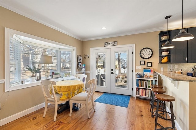 dining room featuring crown molding, french doors, baseboards, and light wood finished floors