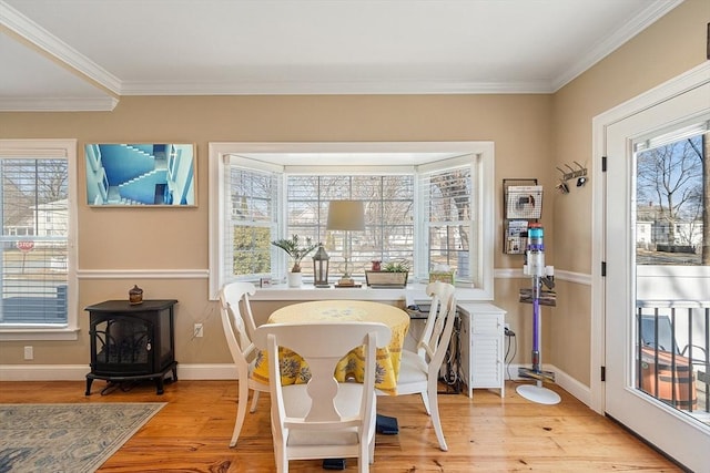 dining area featuring a wood stove, light wood finished floors, baseboards, and a wealth of natural light