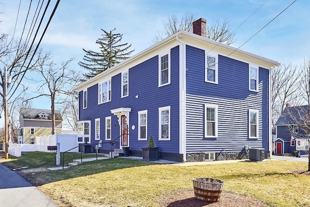 colonial home featuring a front lawn, entry steps, fence, cooling unit, and a chimney