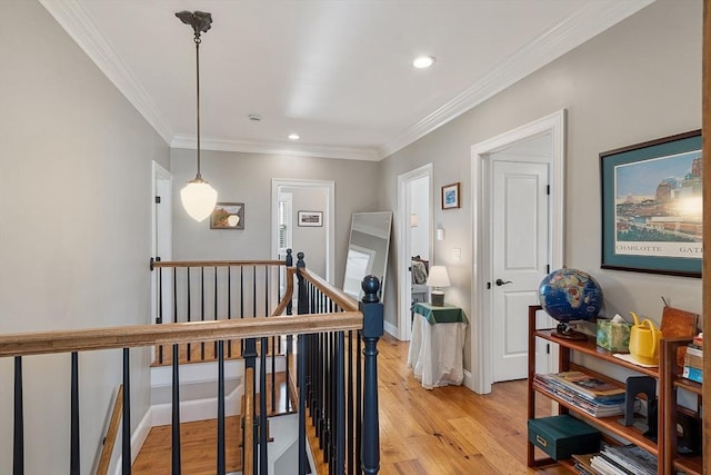 corridor with light wood finished floors, baseboards, ornamental molding, an upstairs landing, and recessed lighting