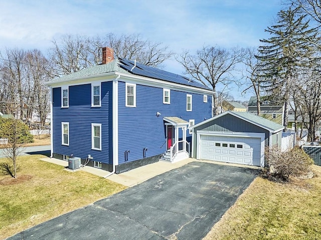 view of home's exterior featuring cooling unit, a yard, a chimney, entry steps, and roof mounted solar panels