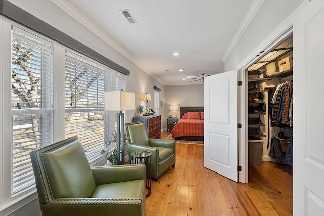 living area featuring visible vents, light wood-style flooring, recessed lighting, ceiling fan, and ornamental molding