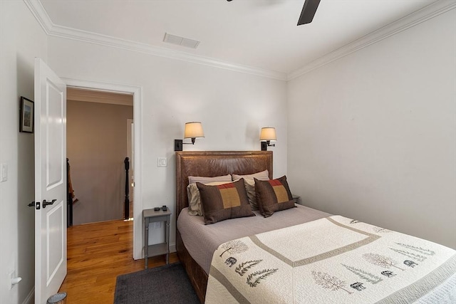 bedroom with a ceiling fan, crown molding, wood finished floors, and visible vents