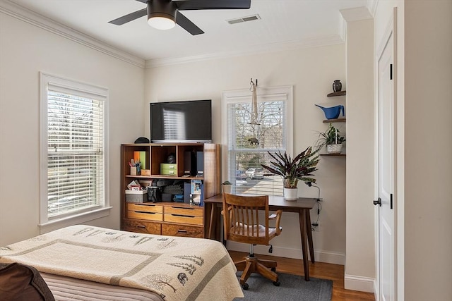 bedroom with visible vents, ornamental molding, wood finished floors, baseboards, and ceiling fan