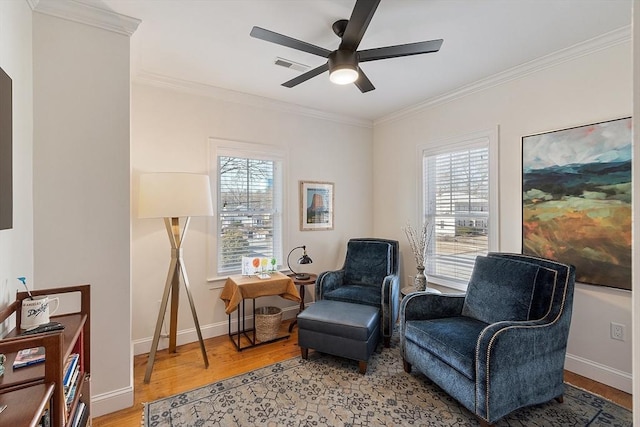 living area with visible vents, a healthy amount of sunlight, ornamental molding, and light wood finished floors