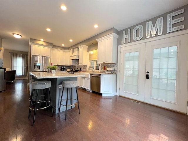 364 Chestnut Hill Rd, Millville, MA 01529 - kitchen featuring stainless steel appliances, custom range hood, a breakfast bar, white cabinets, and backsplash