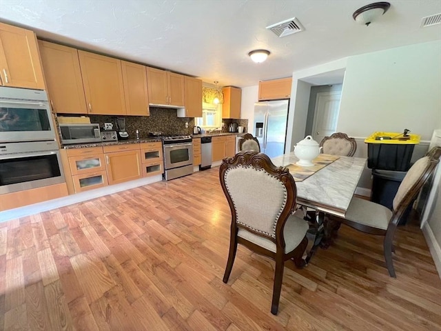 364 Chestnut Hill Rd, Millville, MA 01529 - kitchen with appliances with stainless steel finishes, light wood-type flooring, dark countertops, and decorative backsplash