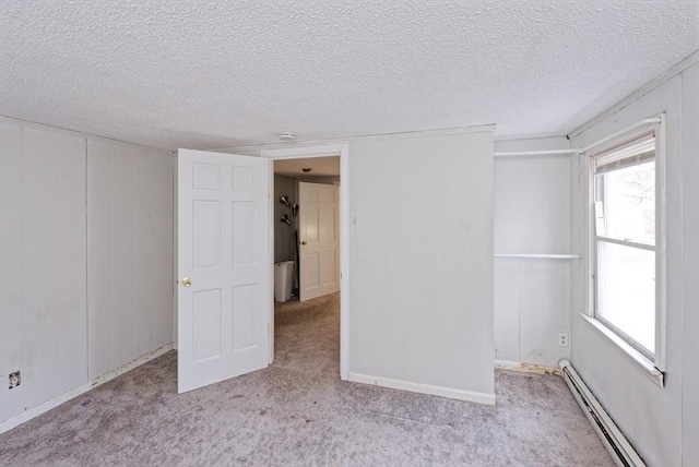 carpeted spare room with baseboard heating and a textured ceiling