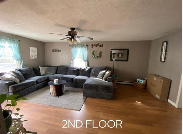 living room with ceiling fan, a textured ceiling, a baseboard heating unit, and hardwood / wood-style floors