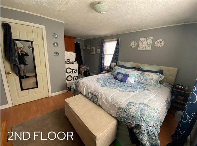 bedroom with hardwood / wood-style floors, ornamental molding, and a textured ceiling