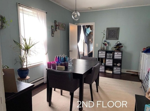 dining area featuring a wealth of natural light, a baseboard heating unit, ornamental molding, and washing machine and dryer