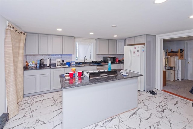 kitchen with a center island, white fridge, tasteful backsplash, dark stone countertops, and gray cabinets