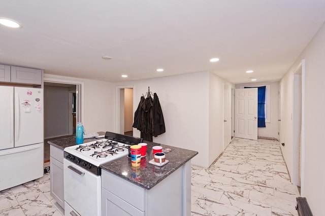 kitchen with white cabinetry, dark stone countertops, a center island, and white appliances