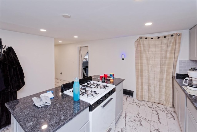 kitchen with white cabinetry, dark stone countertops, a kitchen island, and gas range gas stove