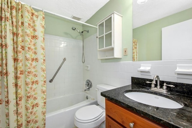 full bathroom featuring shower / tub combo with curtain, tile walls, vanity, a textured ceiling, and toilet