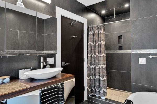 bathroom with tile walls, walk in shower, and vanity