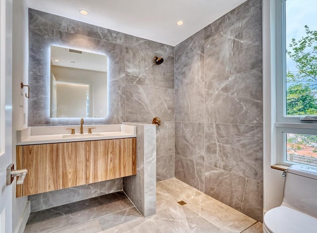 bathroom with toilet, vanity, and a tile shower