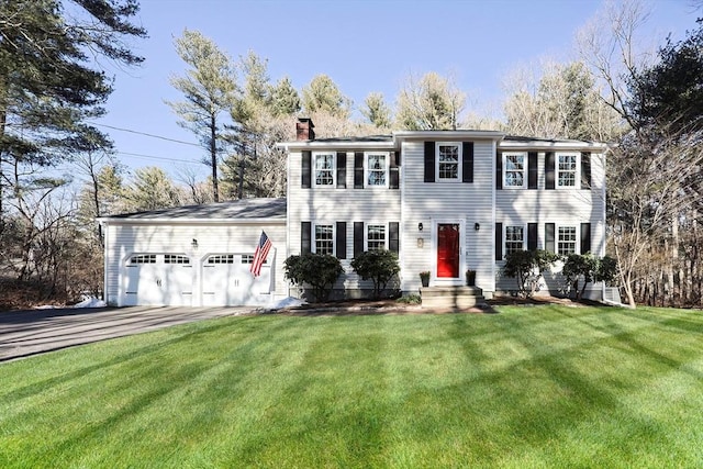 colonial-style house with entry steps, a front lawn, a chimney, and an attached garage