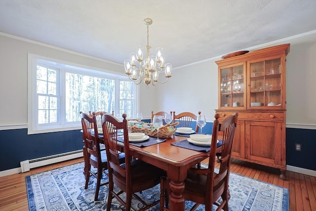 dining space featuring baseboards, wood-type flooring, ornamental molding, a baseboard heating unit, and a notable chandelier