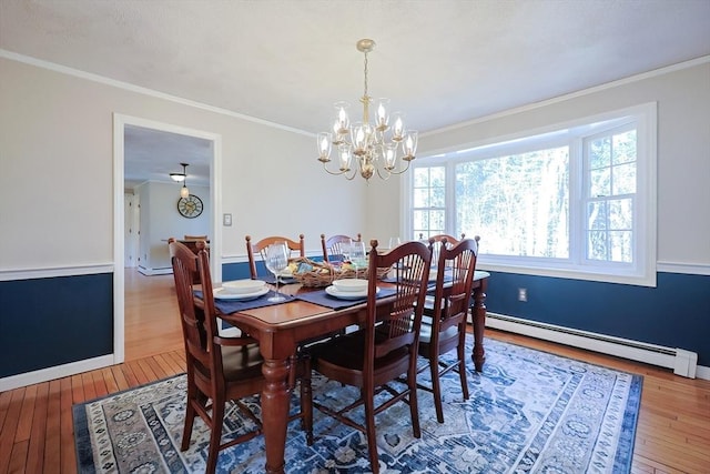 dining room featuring a baseboard heating unit, hardwood / wood-style floors, ornamental molding, and a notable chandelier